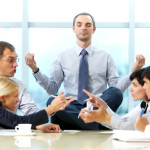 Meditating corporate employee on table with arguing employees