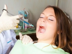 dentist-hand-holding-a-syringe-making-a-numb-shot-for-woman-patient-horizontal-shot-e1390035989666